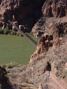 A suspension bridge over the Colorado River. The trail goes through a tunnel before it reaches the bridge.